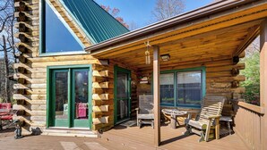 A log cabin with a wooden deck, two large windows, and a covered porch area with outdoor seating. - Rustic Fancy Gap Cabin w/ Blue Ridge Parkway Views (Fancy Gap)