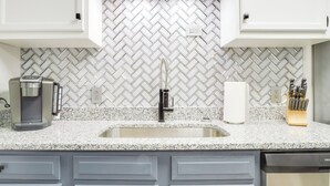 A kitchen with white cabinets, a granite countertop, a coffee maker, a sink, and a knife block. - Modern Townhome: Walk to Tennessee Tech University (Cookeville)