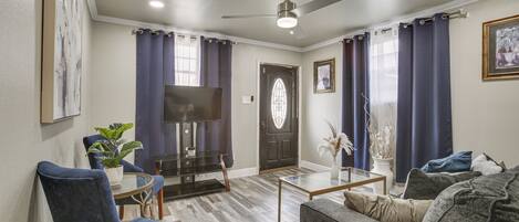 A living room with a sofa, chairs, a coffee table, a TV, and a door with a window.