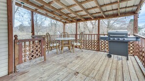 Eine Terrasse im Freien mit Holzboden, einem Grill und Korbstühlen.