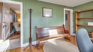 Ein Zimmer mit einer Holzbänkl, einer Stehlampe, einer gerahmten Karte und einem Bücherregal.