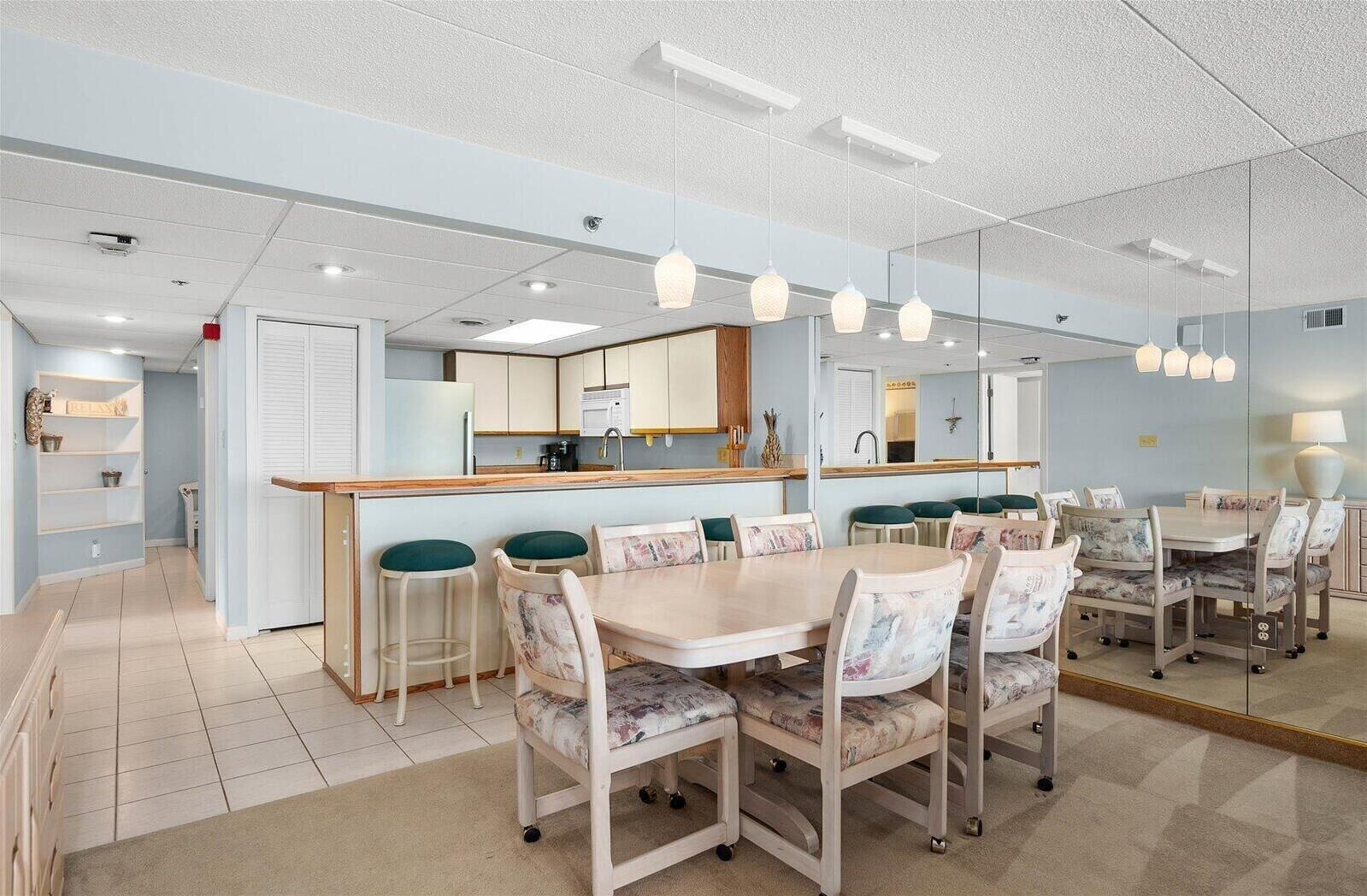 A modern kitchen with a central island, bar stools, and a dining area with a round table and chairs.