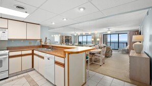 A modern kitchen with a central island, a dining area with a view, and a balcony with a view.