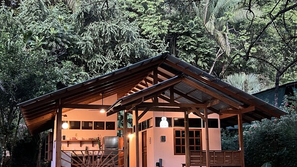 Une cabane en bois avec une véranda, un coin repas et une cuisine.