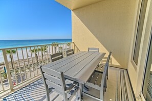 A balcony with a table and chairs, overlooking a beach with palm trees and a clear blue sky. - Unit 0301 3 Bedroom Condo by RedAwning (Panama City Beach)