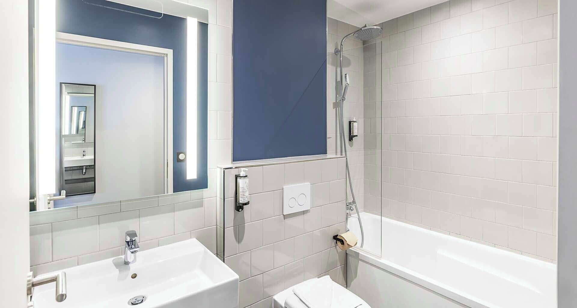 A bathroom with two sinks, a shower, and a mirror.
