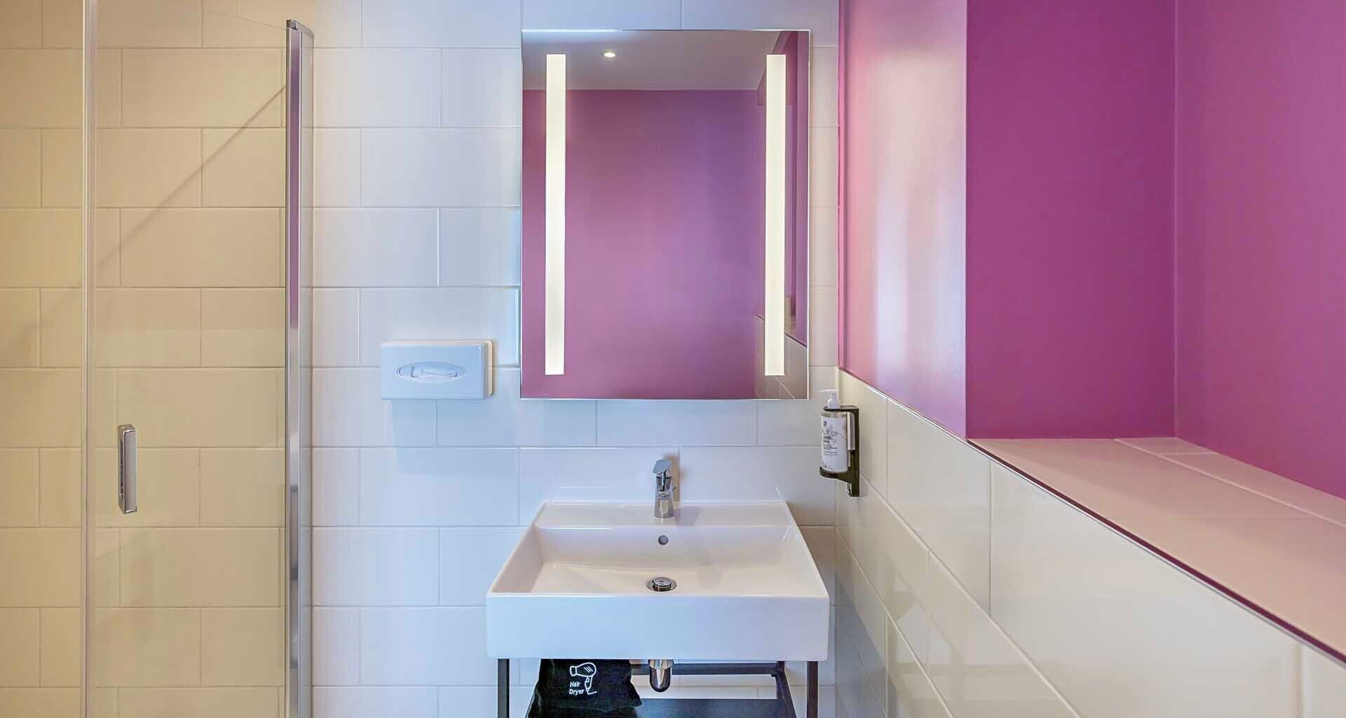 A bathroom with a white sink, a mirror, and a hair dryer.