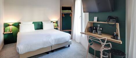 A hotel room with a bed, bedside lamps, a desk with a chair, a TV, and a telephone.