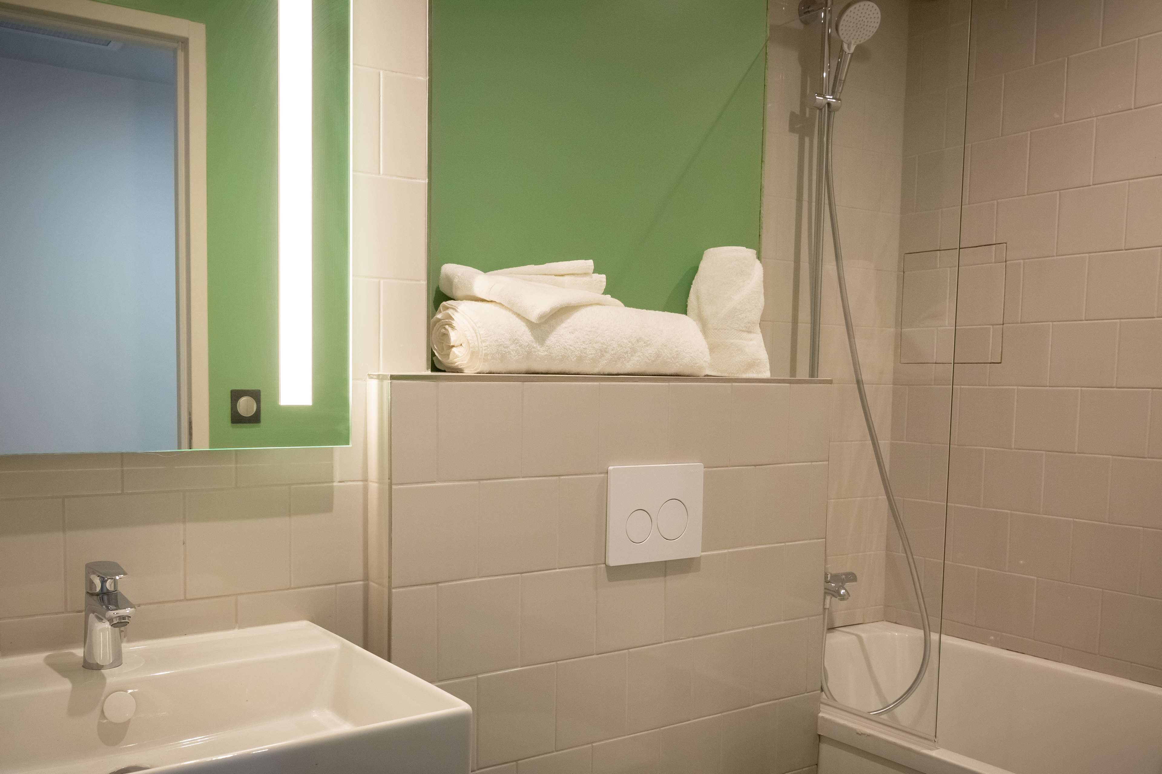 Un bagno con lavandino, specchio, doccia e porta asciugamani.