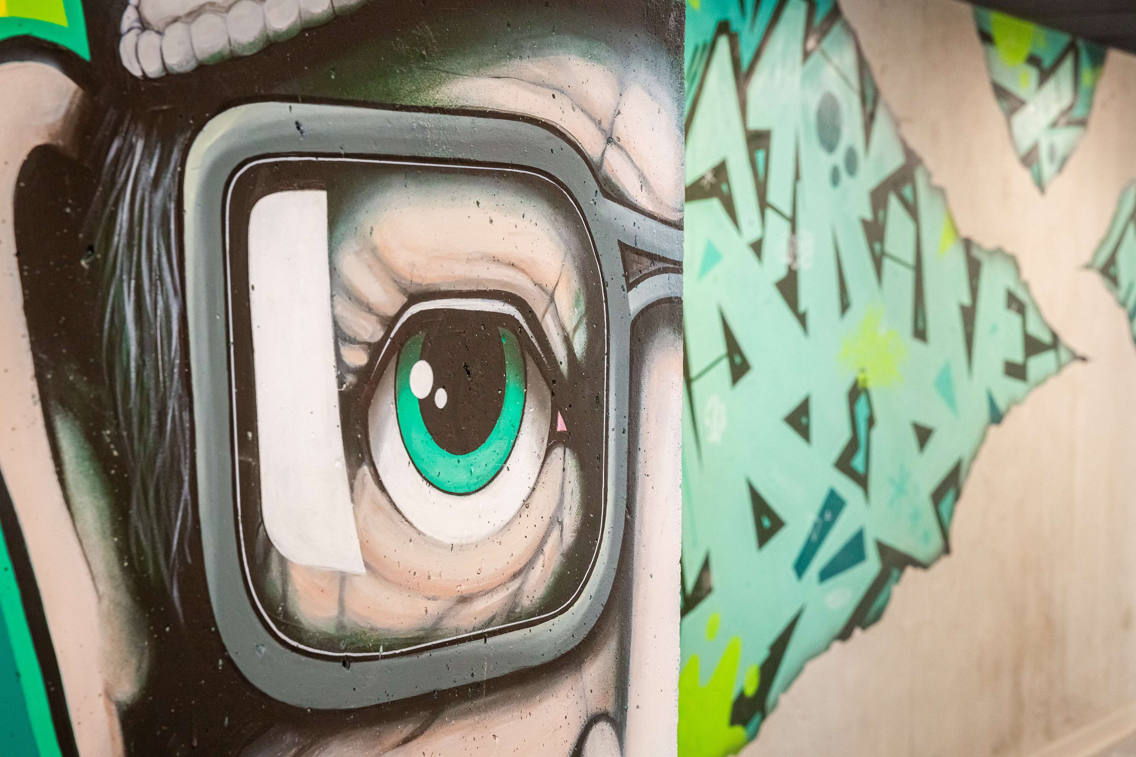 Close-up van een graffiti kunstwerk met een gestileerd oog en een groene iris.