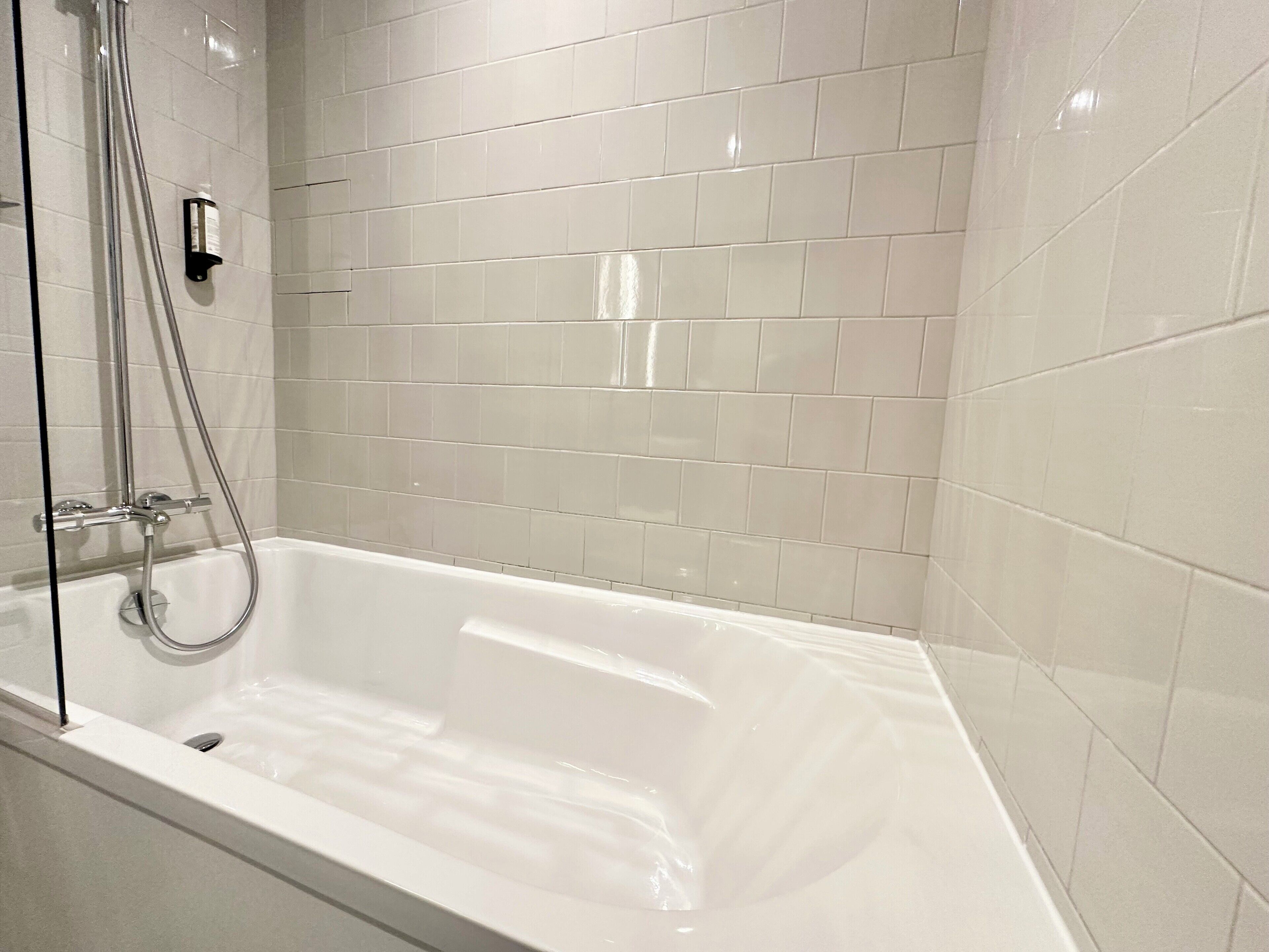 Un baño moderno con una bañera independiente, un cabezal de ducha manual y un grifo de pared.