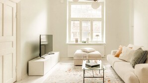 Uma sala de estar minimalista com sofá, mesa de centro e televisão sobre um móvel.