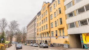Um edifício amarelo com várias janelas e um sinal de faixa de pedestres.