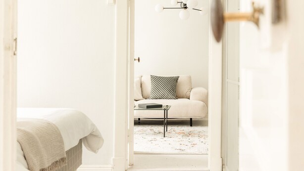 Quarto minimalista com uma cama, um sofá e uma mesinha.