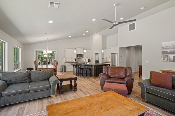 A spacious living area with a sofa, armchair, and coffee table, a kitchen with modern appliances, and a dining area with a table and chairs.
