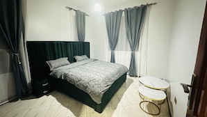 Une chambre à coucher avec un lit, deux tables de chevet et des rideaux.