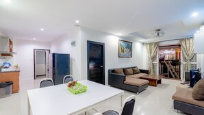 A modern living room with a white table, a sofa, and a dining area.
