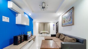 A modern living room with a blue accent wall, a sofa, a wooden coffee table, and a TV.