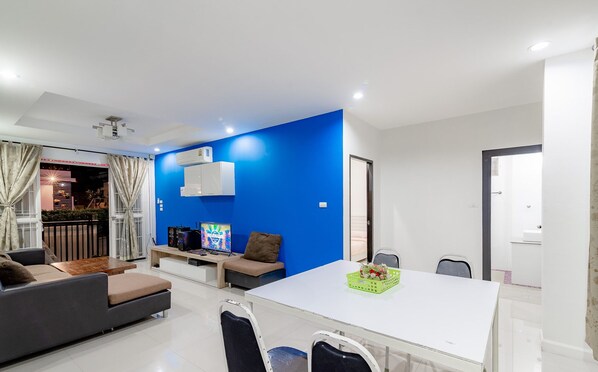 Un salón moderno con una pared de acento azul, una mesa de comedor blanca y un sofá.