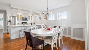 Une cuisine moderne avec des meubles blancs, un îlot central et un coin repas avec des chaises blanches.