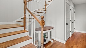 Eine Treppe mit Holzstufen und weißen Geländern führt zu einer Fläche mit einem kleinen Tisch und einem Blumentopf.
