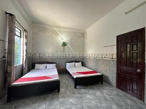 A room with two beds, a wooden door, and a window with curtains. - SPOT ON 1222 Song Han Motel (Da Nang)