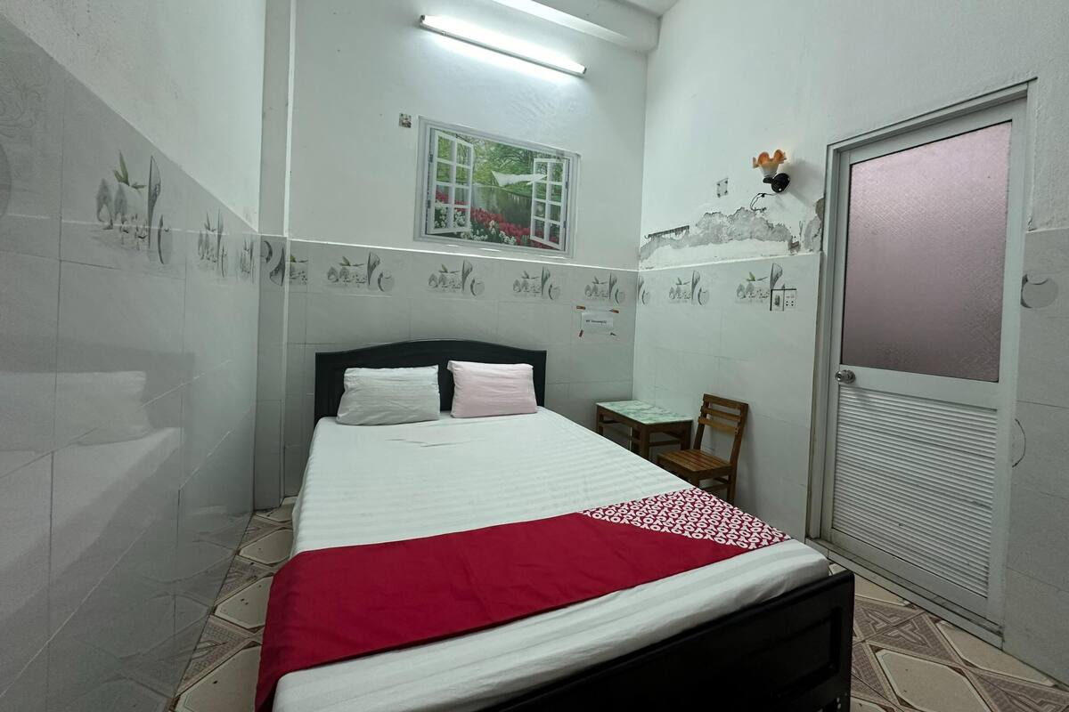 A bedroom with a bed, a chair, a window, and a door.