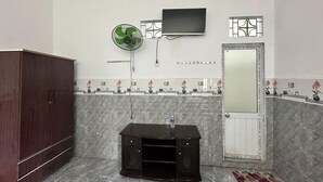 Un baño con pared de mármol, un mueble de madera, un equipo de entretenimiento negro, un televisor montado en la pared y un espejo con marco decorativo.