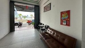 Un vestíbulo con un sofá de cuero marrón, un mostrador de recepción y un cartel en la pared.