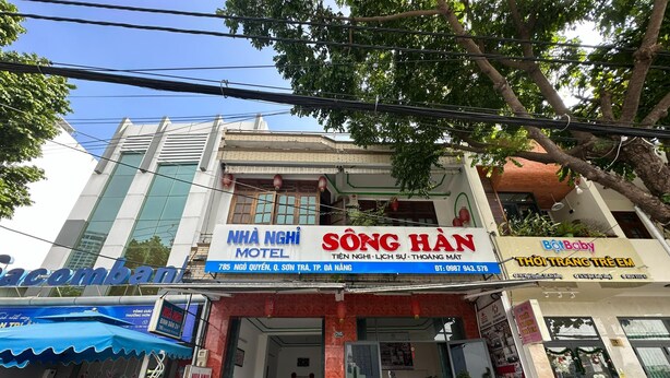 Un edificio con un cartel que indica 'NHÀ NGHI MOTEL' y 'SỐNG HÀN', mostrando un motel y una tienda.