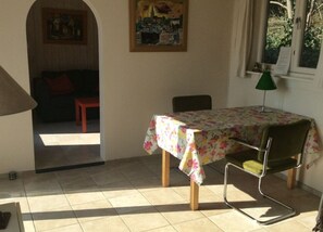 A dining area with a table covered by a floral tablecloth, a green chair, and a lamp. - Very private, just the owner around (Egmond aan den Hoef)