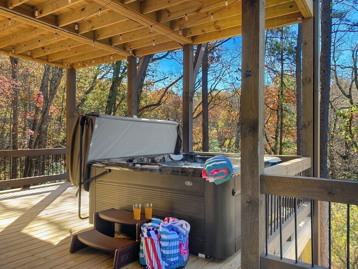 Un jacuzzi en una terraza de madera con vistas a árboles otoñales.