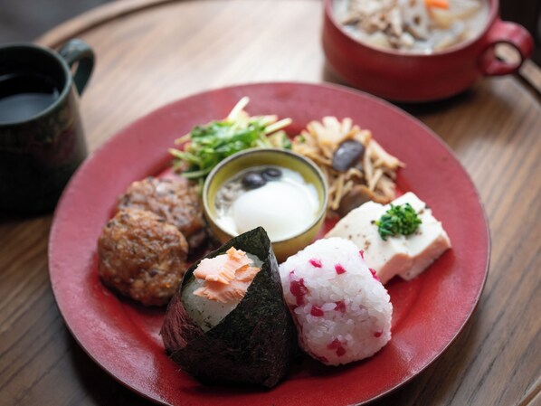 Un plato de sushi, un tazón de sopa y una olla roja al fondo.