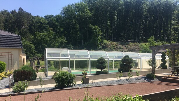 A greenhouse with a pool, surrounded by well-maintained hedges and plants. - Domaine du Moulin (Saint-Avold)