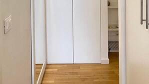 Een witte kast met links een spiegel, een lamp erboven en een metalen handgreep aan de rechterkant.
