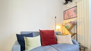 Een moderne woonkamer met een lichtblauwe bank, een houten vloer en een wit plafond met zichtbare balken.