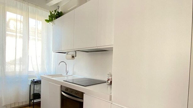 Een moderne keuken met witte kasten, een ingebouwde oven en een zwart aanrecht.
