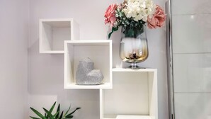Un intérieur moderne avec des étagères blanches, un vase de fleurs et une plante verte.