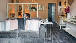 A living room with a grey sofa, a white coffee table, and a bookshelf.