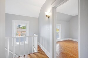 A spacious room with a wooden floor, white walls, and a white railing.