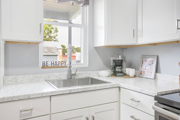 A modern kitchen with white cabinetry, a stainless steel sink, and a coffee maker. - 3 Bedroom 2 bath home near Notre Dame(123ND) (South Bend)