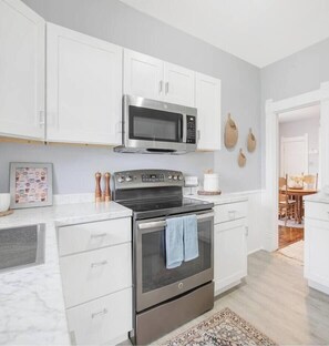 A modern kitchen with white cabinetry, a stainless steel oven, and a microwave. - 3 Bedroom 2 bath home near Notre Dame(123ND) (South Bend)