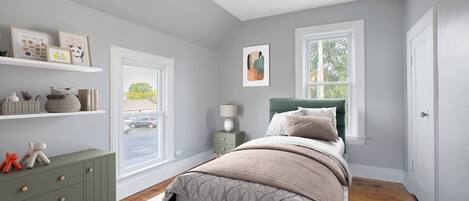 A bedroom with a bed, bedside tables, a dresser, and a window.