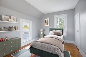 Une chambre à coucher avec un lit, des tables de chevet, une commode et une fenêtre.