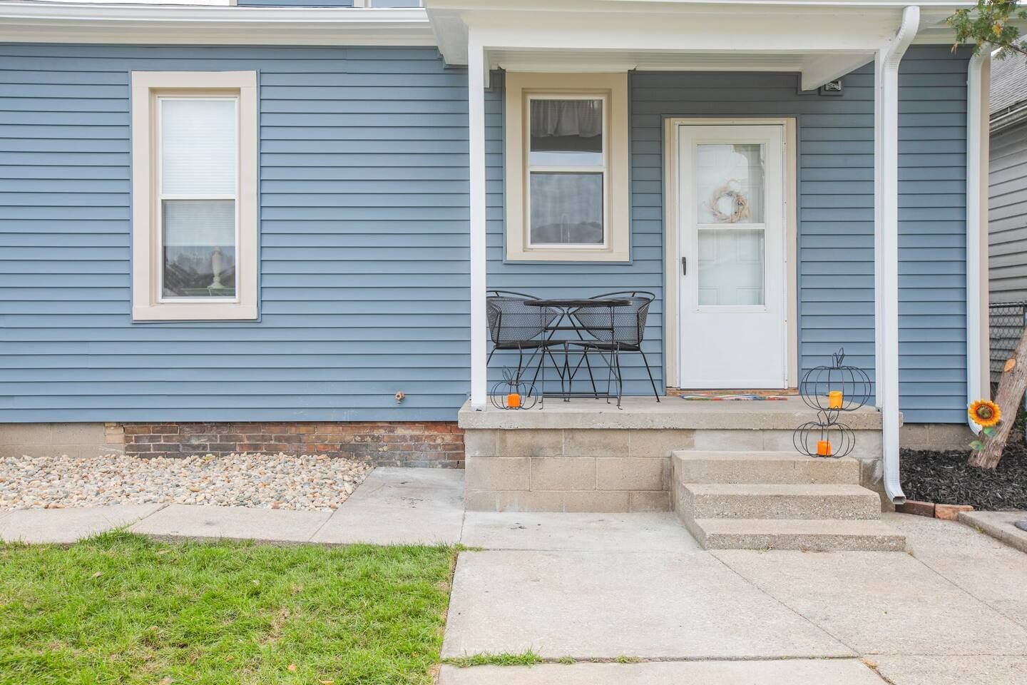 A residential house with a front porch, a door, and two windows.