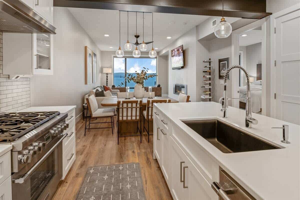Una cocina moderna con una isla grande, muebles blancos y vistas al océano.