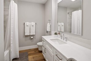 Une salle de bain moderne avec un lavabo blanc, un miroir et un rideau de douche.