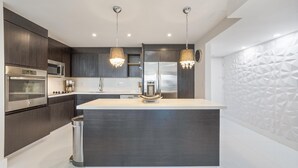 Una cocina moderna con armarios oscuros, electrodomésticos de acero inoxidable y una isla central.