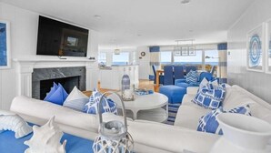 Un salon moderne avec une cheminée, un téléviseur et une vue sur l’océan.