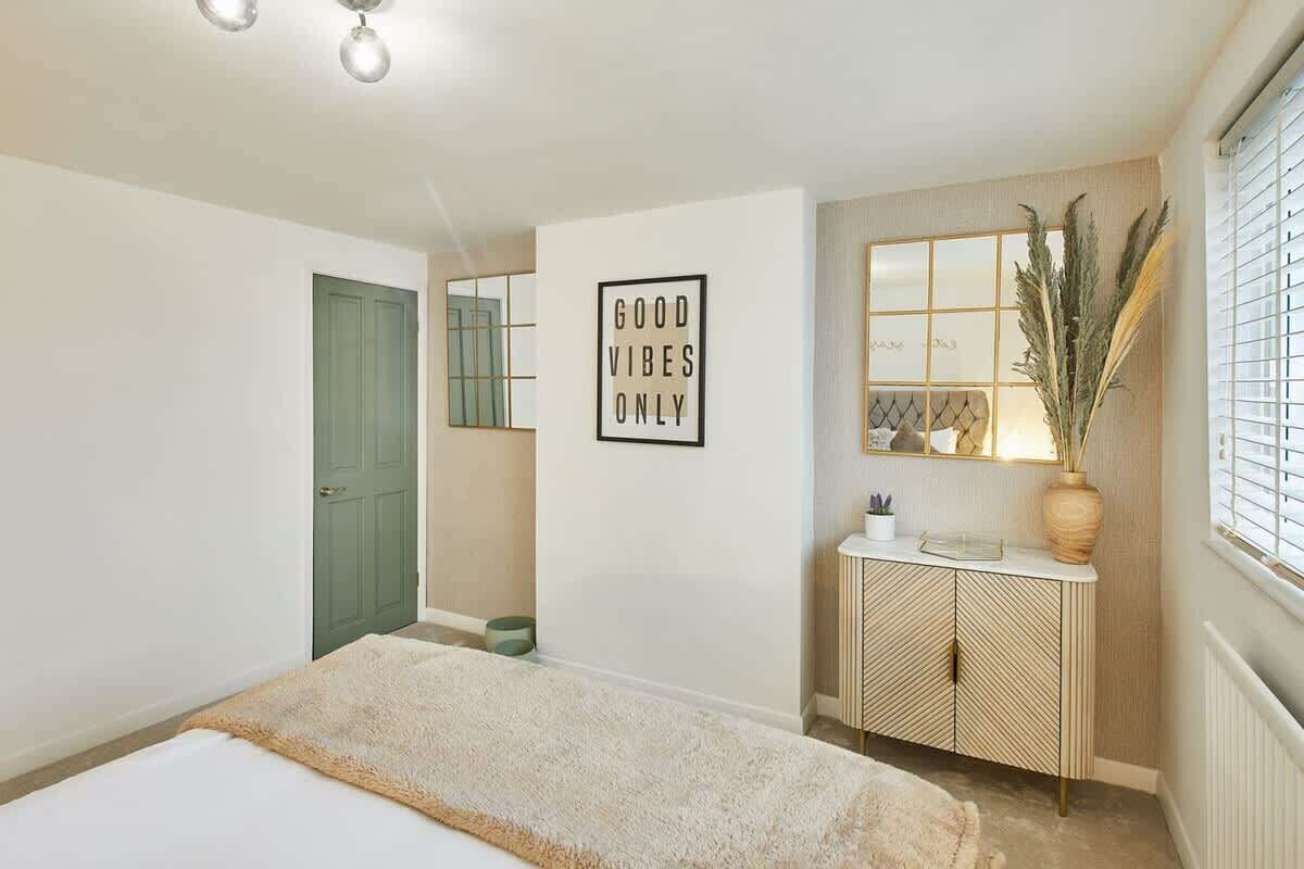 A bedroom with a bed, a green door, a wall-mounted cabinet, and a framed sign.